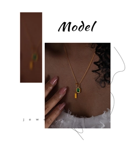 Detail shot of a model wearing a gold necklace with green gemstone and rectangle charm
