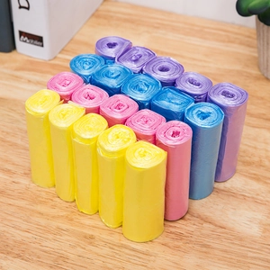 Colorful roll-style plastic garbage bags for home cleaning on a wooden surface