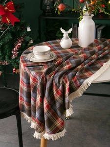 Close-up of festive plaid tablecloth with cream tassels in a Christmas setting
