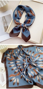 Détail d'un foulard en soie bleue présentant d'élégants motifs de plumes marron et blanc
