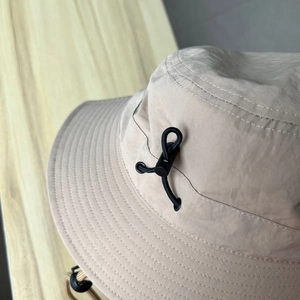 Detail of adjustable elastic drawstring and buckle on beige outdoor sun hat fabric