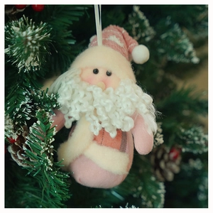 Detail of pink Santa plush ornament hanging on Christmas tree with knit texture