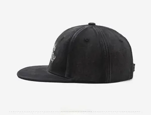 Detail shot of black flat brim baseball cap with white embroidery on washed canvas