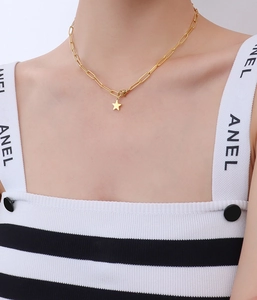 Close-up of golden paperclip chain necklace with a solid star pendant on a model