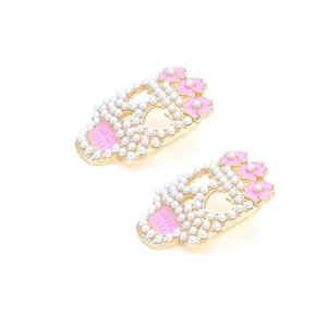 Detailed close-up of skull earrings with white pearls and pink enamel flowers