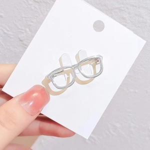 Detailed view of a silver glasses shaped brooch pinned on a white card display