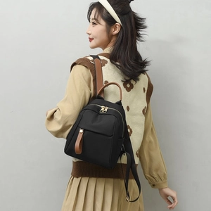 Elegante zaino da donna in nylon nero con dettagli in pelle marrone e finiture dorate