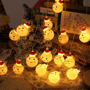 Close-up of LED snowman string lights with red hats on a snow-covered Christmas tree