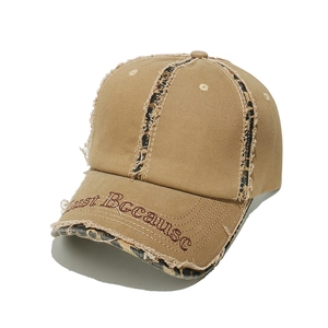 Close-up of distressed khaki cotton baseball cap with leopard trim and Just Because embroidery