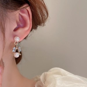 Macro shot of gold dangle earrings featuring elegant pearls and sparkling rhinestones