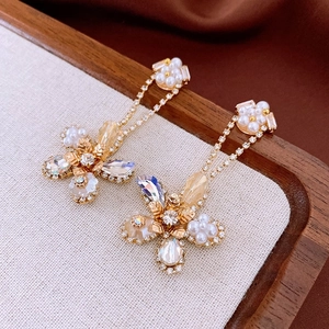 Detailed shot of vintage gold flower earrings with crystals, pearls and tassels on wood