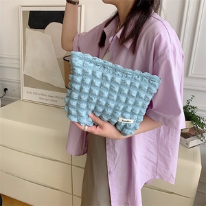 Detail view of light blue bubble texture cosmetic bag featuring Sozakka brand woven label
