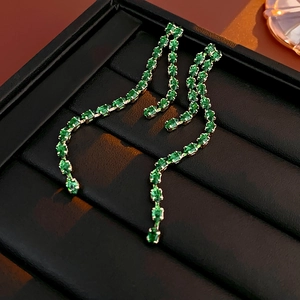 Close-up of elegant green gemstone drop earrings in S-shaped silver setting