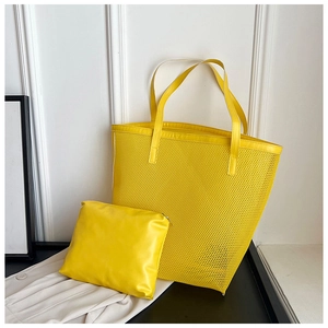 Detail of bright yellow mesh tote bag and matching mini zipper pouch on a black surface