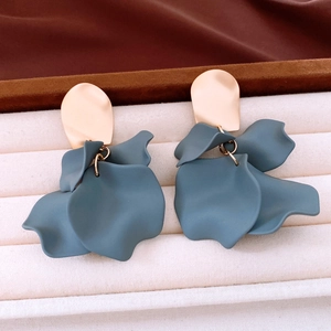 Detail of matte grey-blue petal drop earrings with gold metal studs on a display tray