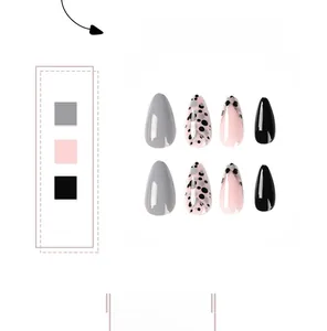 Detail of almond-shaped press-on nails with grey, pink polka dots and gold line accents