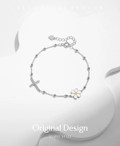 Detail of s925 silver bracelet with sparkling cross and daisy charms on white prop