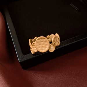 Macro detail of matte gold oval ring with hammered texture on black jewelry box