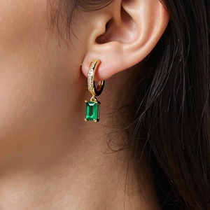Dettaglio di orecchini placcati oro 18K con zircone verde smeraldo e pietre bianche lucide