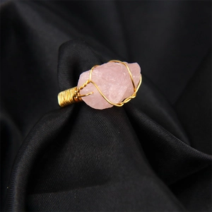 Macro detail of handmade gold wire-wrapped pink crystal raw stone adjustable ring