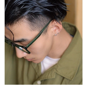Close-up of dark green oversized glasses frames on male model wearing olive shirt
