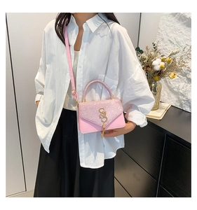Detailed shot of pink glitter crossbody bag featuring an S-shaped metal buckle and tassel