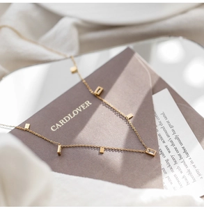 Detail of gold titanium steel necklace featuring rectangular charms and zircon stones