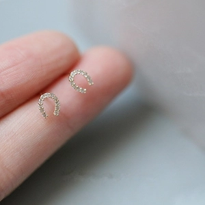Gros plan de boucles d'oreilles fer à cheval en argent S925 avec zircons sur un doigt