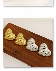 Detailed close-up of heart-shaped shell earrings in polished gold and silver finishes