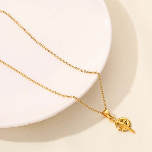 Detail of 18K gold plated necklace featuring a geometric cutout moon pendant on a white tray