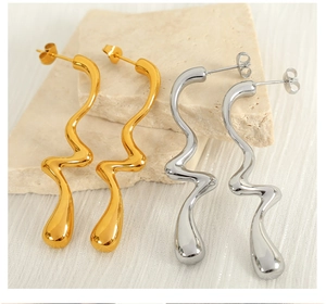 Detail view of wave-shaped long metal earrings in polished gold and silver finishes