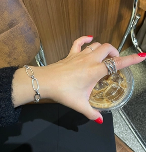 Close-up of retro 925 sterling silver chain bracelet and layered rings on model
