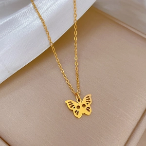 Close-up of a gold hollow butterfly pendant necklace on soft beige silk background
