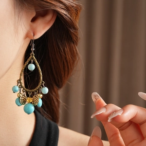 Detail of vintage bronze drop earrings with turquoise beads and metallic tassels