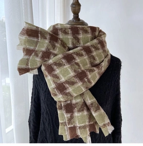 Detail of winter houndstooth scarf with brown and olive green fringe edges