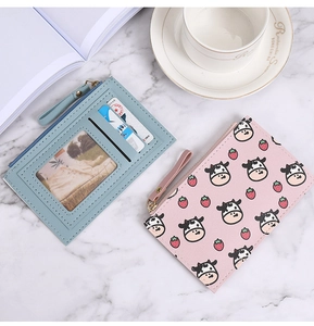 Detail of blue card holder and pink cow print wallet on marble surface with coffee cup