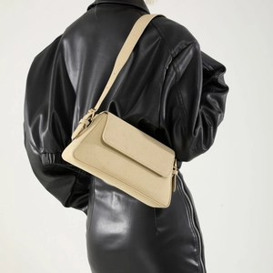 Detail of beige suede baguette shoulder bag with adjustable strap and metal buckle
