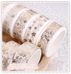 Macro detail of gold foiled washi tape set with floral patterns on a wooden tray