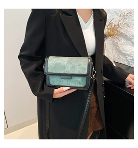 Detail of retro green suede and black leather patchwork bag with golden metal hardware