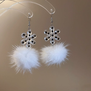 Detail showing acrylic flower and white pompom drop earrings on a display stand