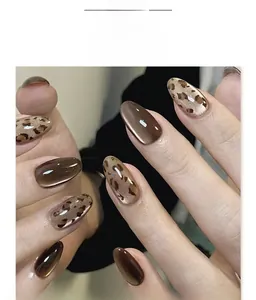 Gros plan sur faux ongles amande courts avec motifs œil de chat marron et léopard