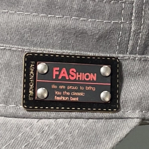 Grey washed flat top cap with black leather label, fashion text and silver rivets detail