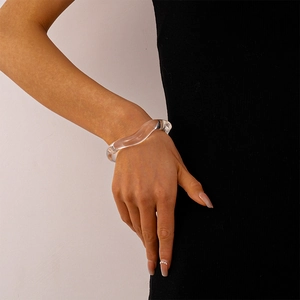 Close-up of clear acrylic wavy bangle on wrist with elegant minimalist design