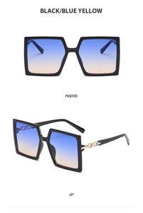 Detail of oversized black frames with blue and yellow gradient lenses and gold chain temples