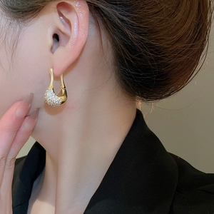 Gros plan de boucles d'oreilles dorées en forme de U avec zircons sertis sur mannequin