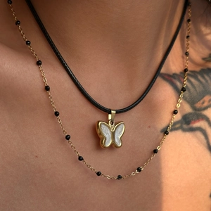Close-up of 18k gold butterfly pendant and layered necklace worn by a model