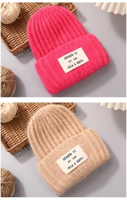 Detail of chunky knit rabbit fur beanie showing texture and seasonal fabric label