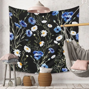 Detail of bohemian wall tapestry with blue cornflowers and white daisies on black fabric