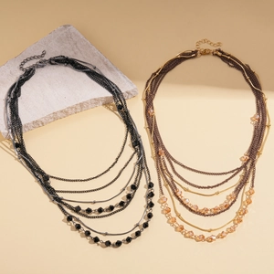 Detailed close-up of layered glass bead necklaces with mixed metal chains and woven cords
