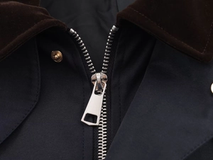 Detail of dark blue windbreaker featuring a brown corduroy collar and silver metal zipper